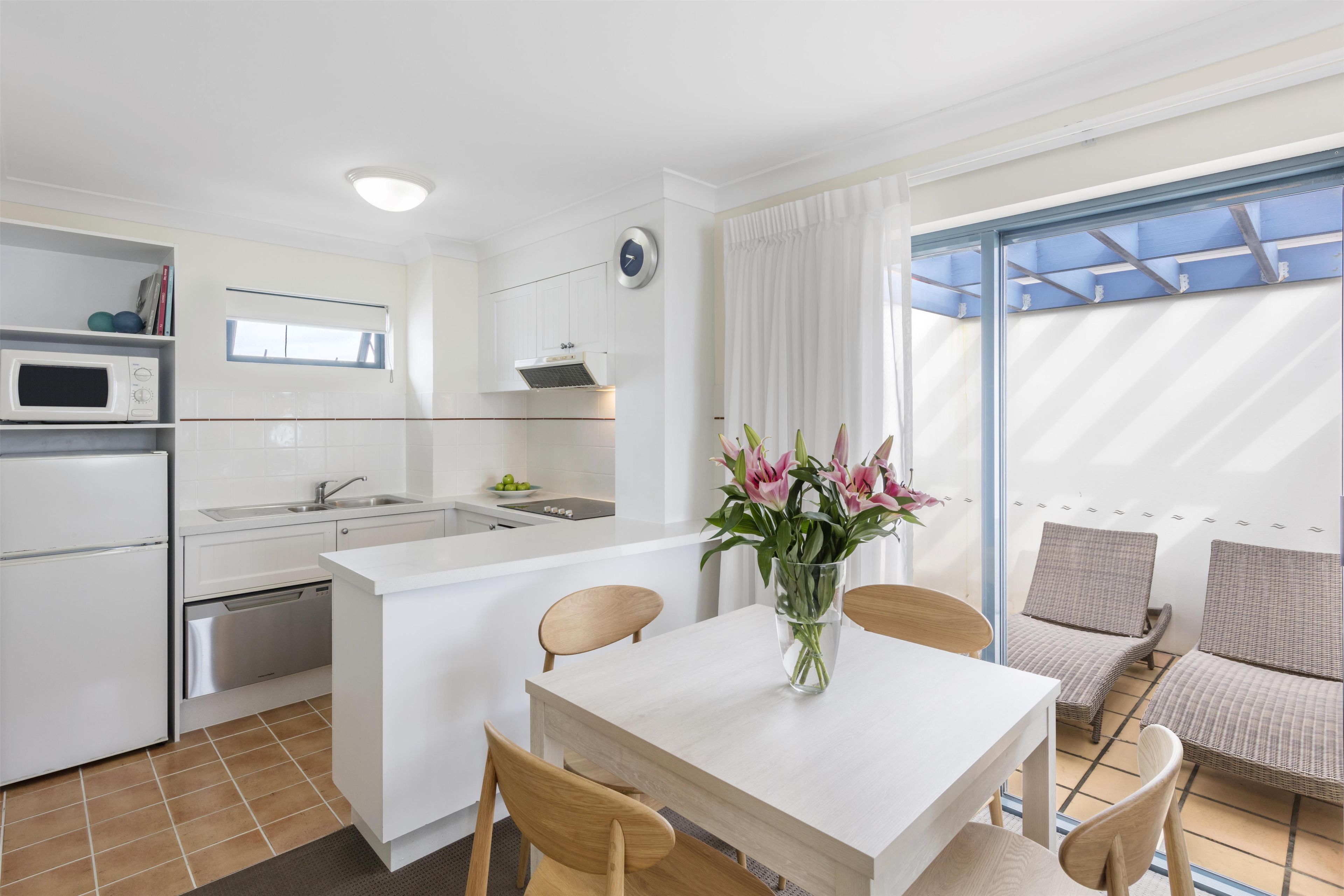 Una cocina moderna con una isla central, un comedor con mesa y sillas, y una sala de estar con vistas.