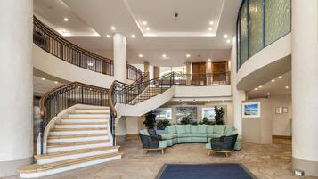 A spacious lobby with a central staircase, a curved seating area, and a second-floor balcony.