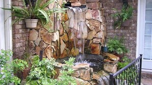 A stone waterfall feature with hanging planters and a brick wall. - Shalom House Bed and Breakfast (Tifton)