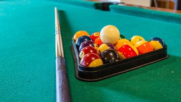 A pool table with a cue stick and a rack of billiard balls.
