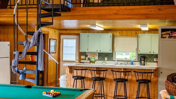 A cozy cabin with a pool table, a kitchen area, and a spiral staircase. - Shalom House Bed and Breakfast (Tifton)