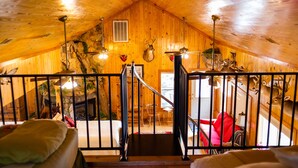 A wooden interior with a staircase leading to a lower level, a fireplace, and mounted animal heads on the walls. - Shalom House Bed and Breakfast (Tifton)