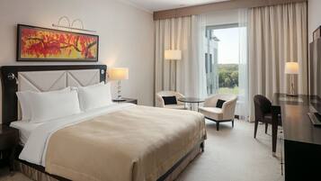 A hotel room with a large bed, two bedside tables, a desk, a chair, and a large window with curtains.
