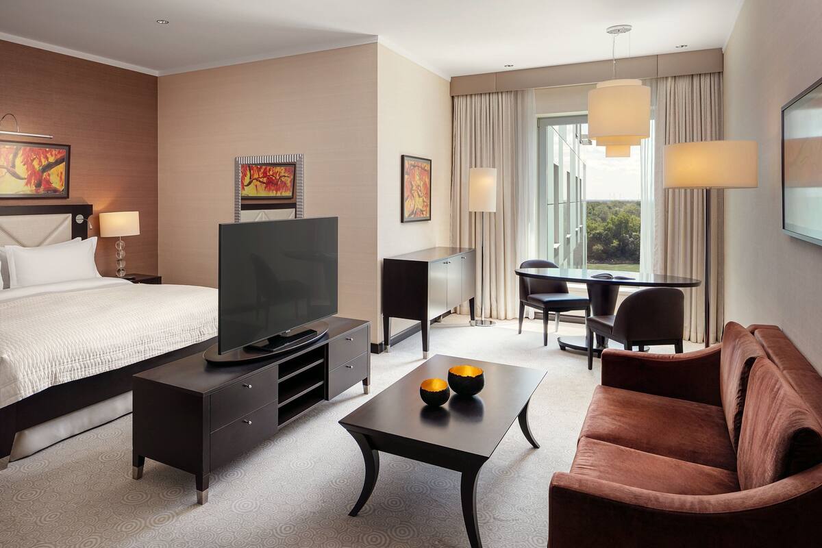 A hotel room with a bed, TV, desk, and sofa.