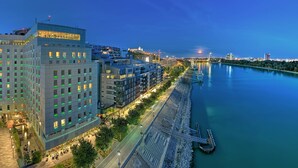 Ein modernes Hotel mit Blick auf einen Fluss, einem Anleger und einer Brücke im Hintergrund.
