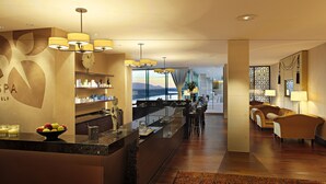 Een moderne hotel lobby met een receptiebalie, zithoek en uitzicht op het omliggende landschap.