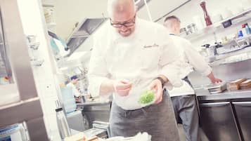 A chef preparing food in a professional kitchen with stainless steel appliances and a water dispenser.