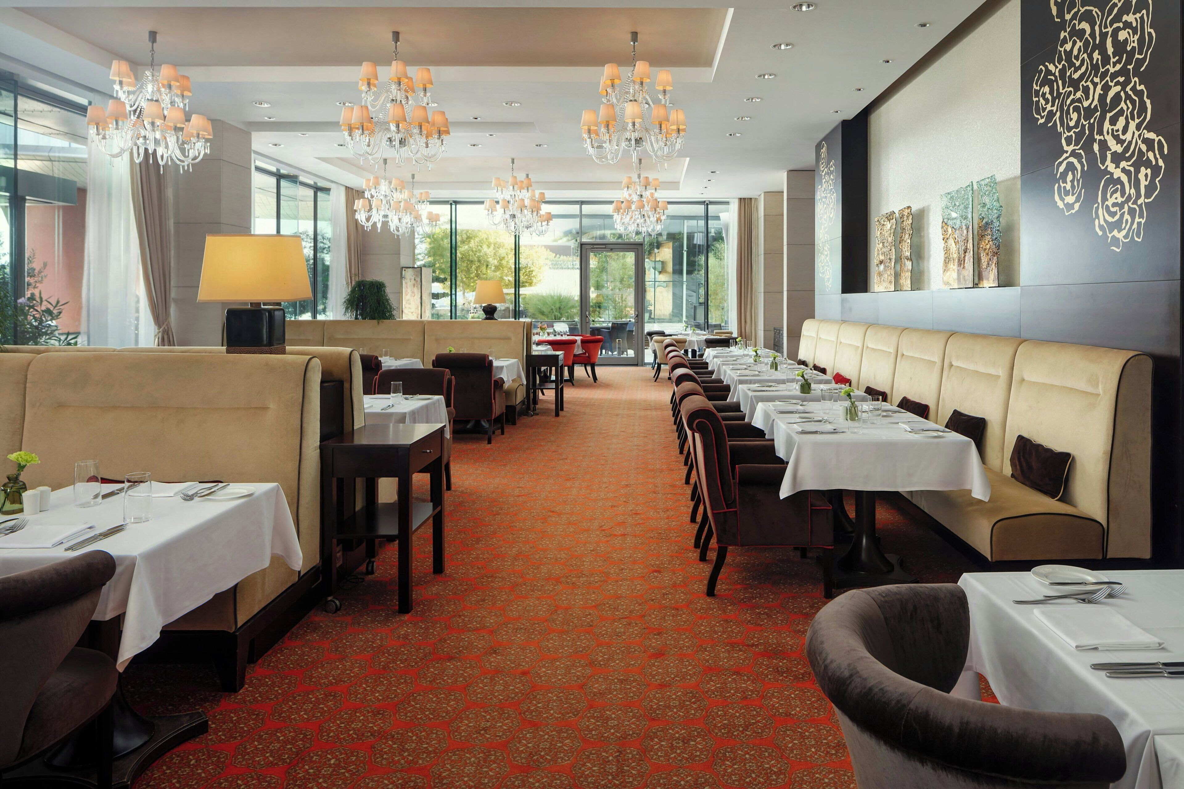 A restaurant with a long table, booths, and a patterned carpet.