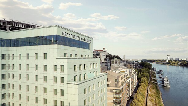 Ein modernes Hotelgebäude mit Glasfassade und dem Schriftzug 'Grand Hotel River Park'.