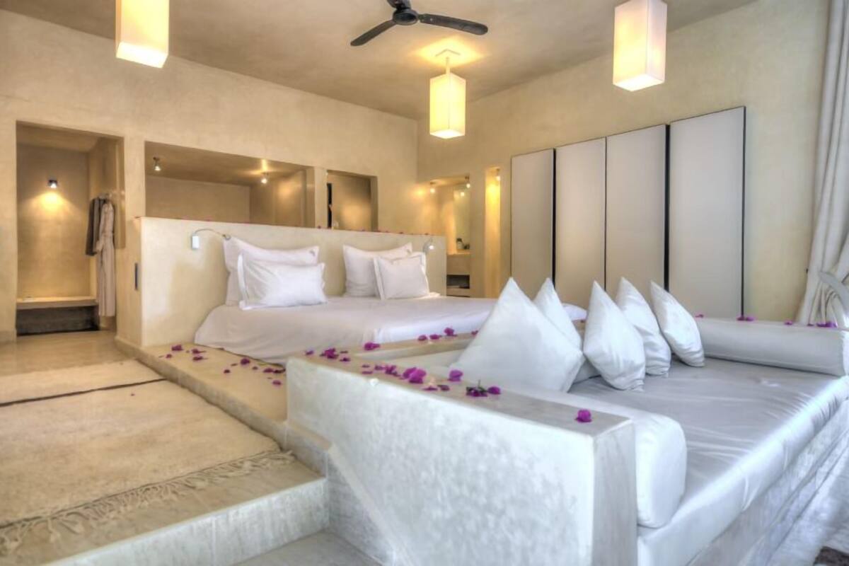 A modern hotel room with a large bed, a sitting area, and a walk-in closet.