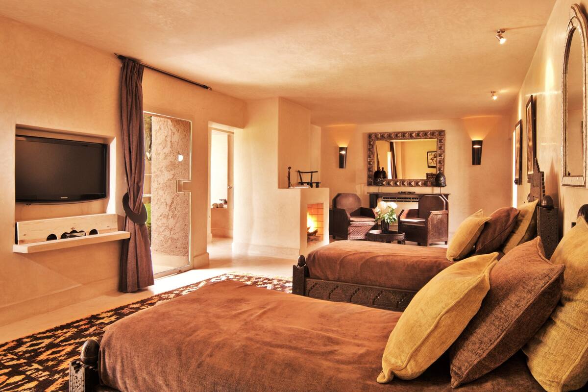 A hotel room with two beds, a TV, a fireplace, and a large mirror.