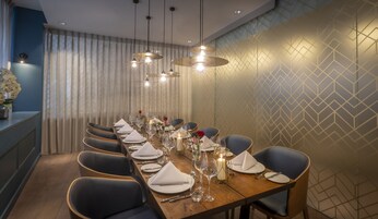 A long dining table set with chairs, candles, and flowers, in a room with patterned wallpaper and a blue accent wall.