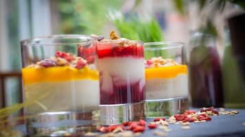 Drei Schichtdesserts in klaren Gläsern, verziert mit Nüssen und Beeren, auf einer dunklen Oberfläche mit verstreuten Nüssen und Beeren rundherum.