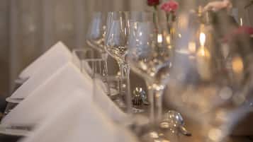 A table set with multiple wine glasses and a rose in a vase.