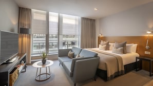 Een moderne hotelkamer met een groot bed, een bank, een televisie en een balkon met uitzicht.