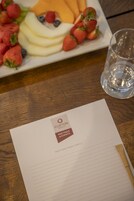 A plate of fruit and a glass of water on a wooden table with a hotel meeting and events brochure.
