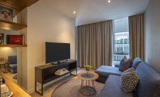 Uma sala de estar moderna com televisão de tela plana, um sofá, uma mesa de centro e uma estante de livros.