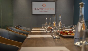 Una mesa de conferencias con sillas vacías, cristalería y un plato de fresas en el Clayton Hotel, London Wall.