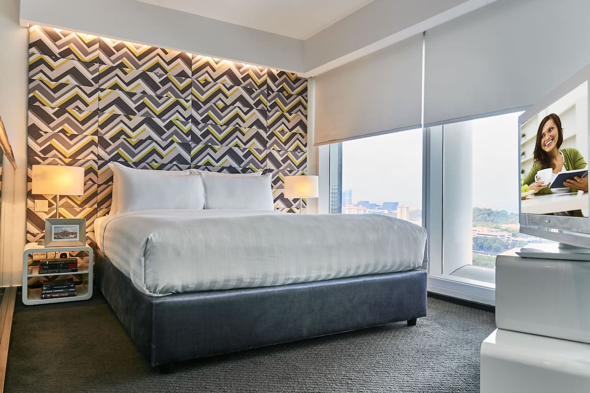 Une chambre d’hôtel moderne, dotée d’un grand lit, d’une télévision et offrant une vue sur la ville.