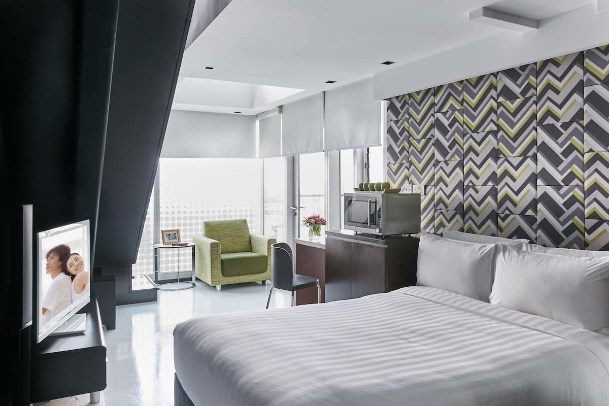 Une chambre d’hôtel moderne équipée d’un grand lit, d’une télévision, d’un bureau et d’une chaise.