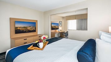 A hotel room with a large bed, a desk, and a television displaying a cityscape.