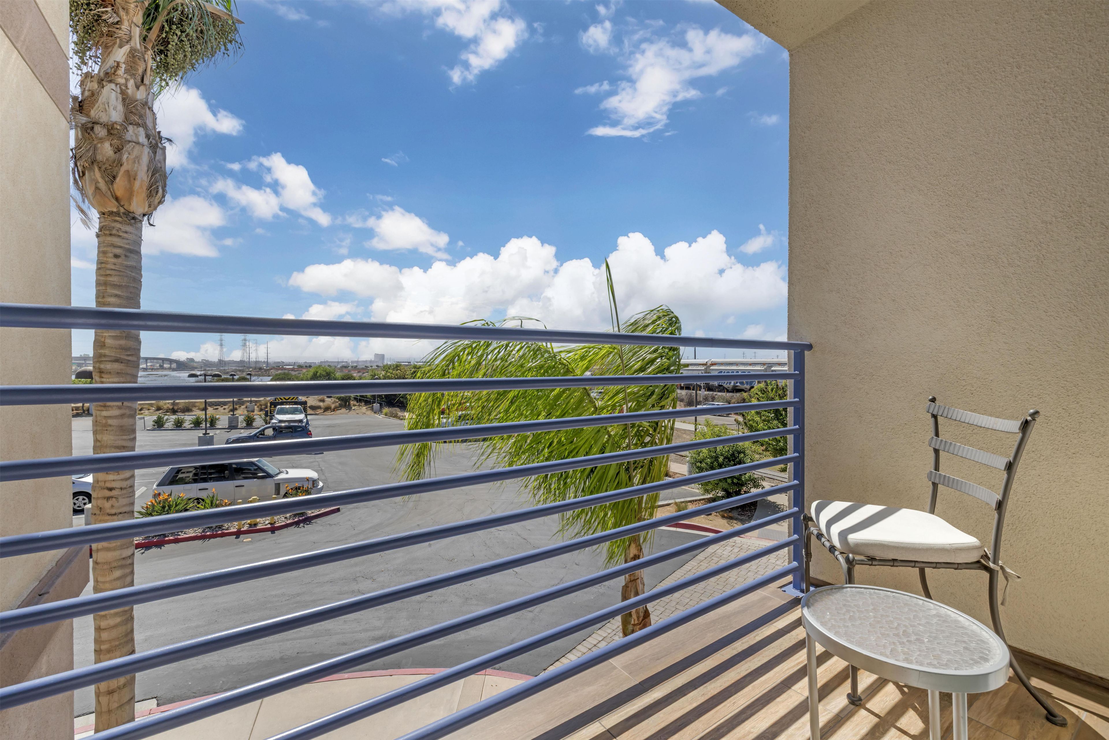 A balcony with a view of a parking lot and a cityscape.