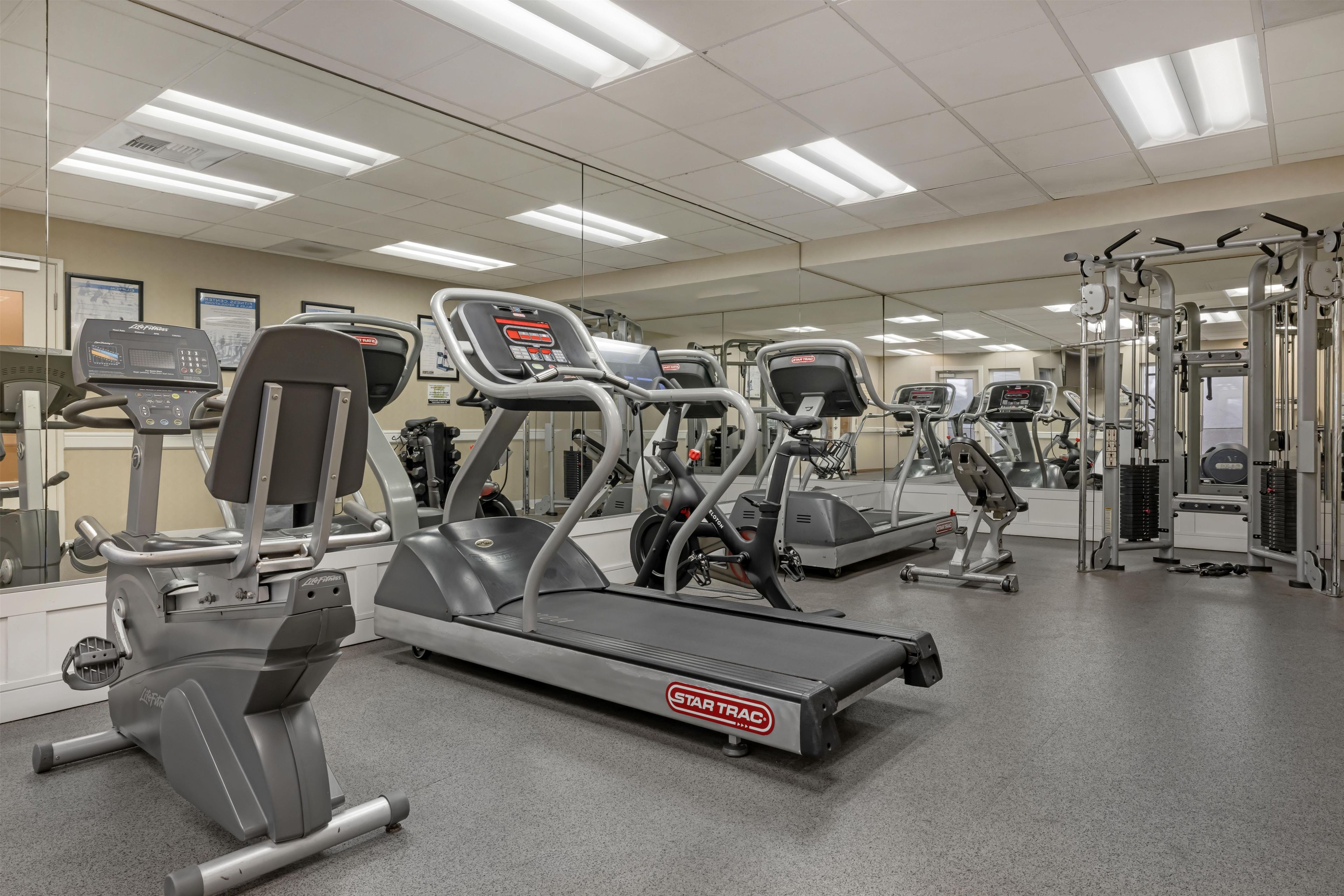 Une salle de sport équipée de plusieurs tapis de course, de plusieurs appareils de musculation elliptique et de matériel de musculation.