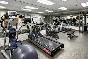 A gym with treadmills, elliptical machines, and a mirrored wall.