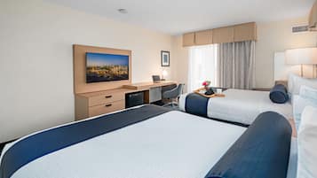 Une chambre d’hôtel avec deux lits, un bureau, une chaise, une lampe et une fenêtre avec des rideaux.