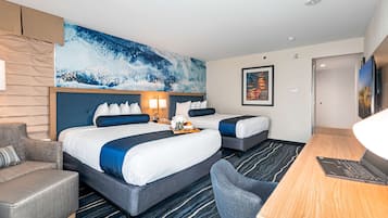 Une chambre d’hôtel avec deux lits, un bureau, une chaise, un grand tableau abstrait et un téléviseur.