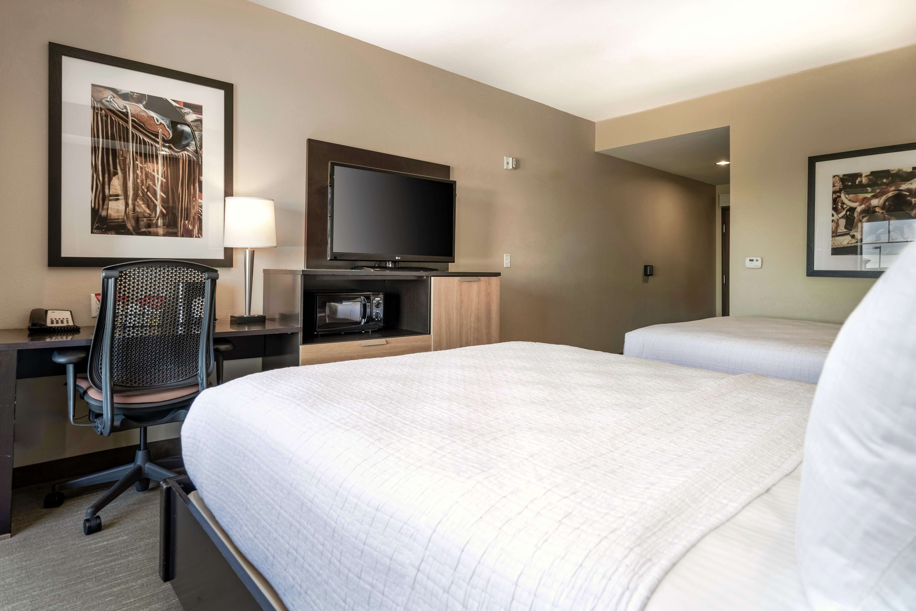 Habitación de hotel con una cama grande, un escritorio con silla, un televisor de pantalla plana y obras de arte en las paredes.