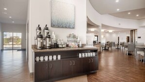 A modern hotel lobby with a coffee station, seating area, and a large window offering a view.