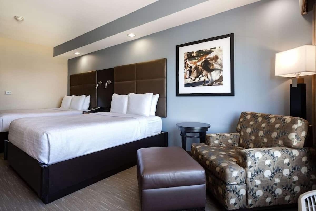 Ein Hotelzimmer mit Doppelbett, einer Couch, einem Sessel, einem kleinen Tisch und einem gerahmten Bild an der Wand.