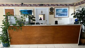 A reception desk with a clock, a notice board, and a framed landscape painting.