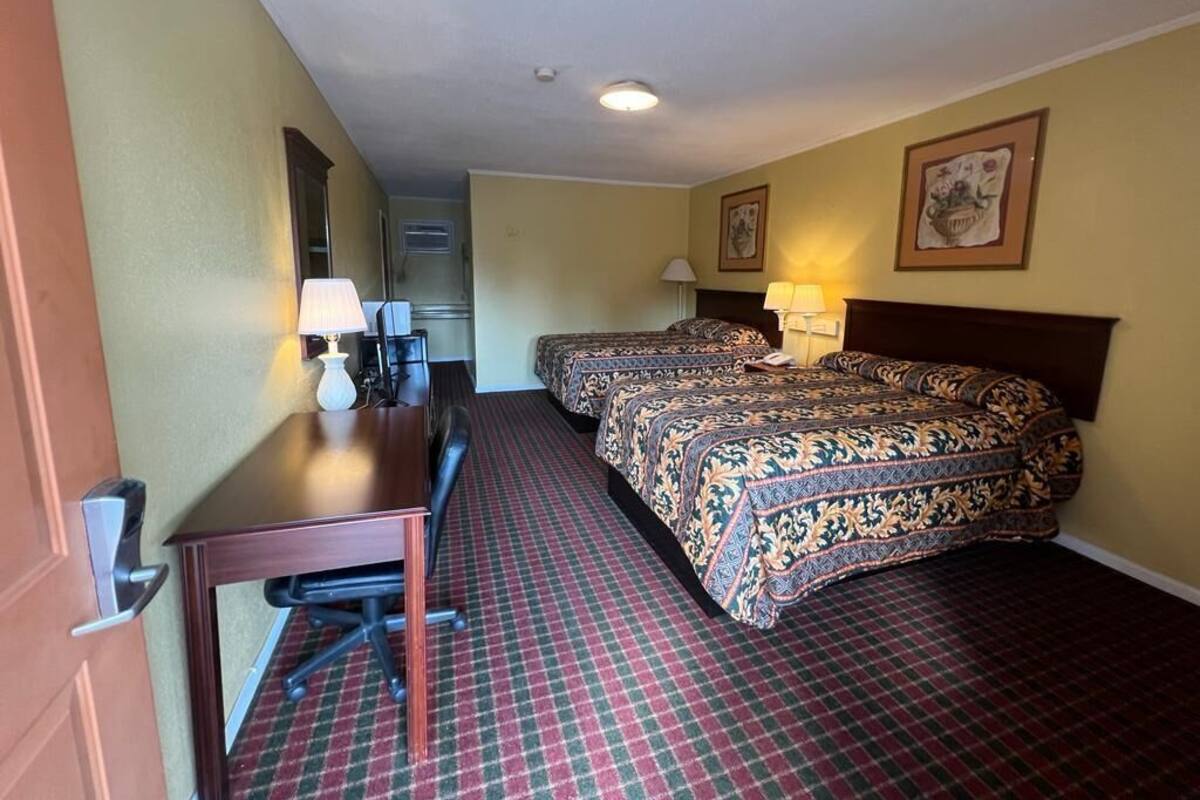 Habitació d'hotel amb dos llits, una taula i una cadira.