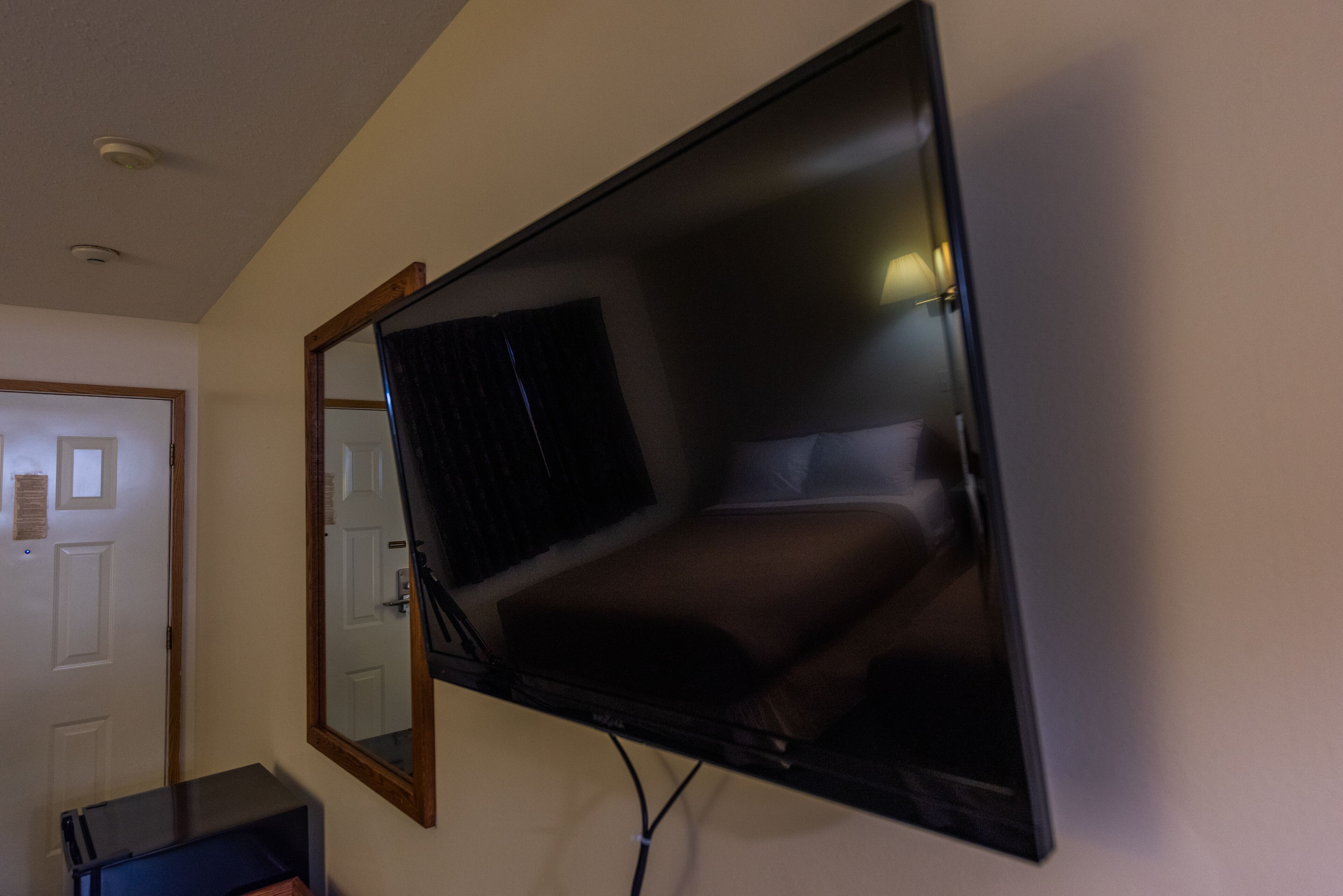 Un televisor de pantalla plana montado en una pared en una habitación con una puerta y una mesita.