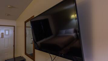 Un televisor de pantalla plana montado en una pared en una habitación con una puerta y una mesita.