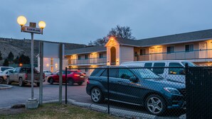 Un motel con área de estacionamiento cercada, un letrero que dice 'Ranchland' y un edificio con varias ventanas y un pequeño porche.