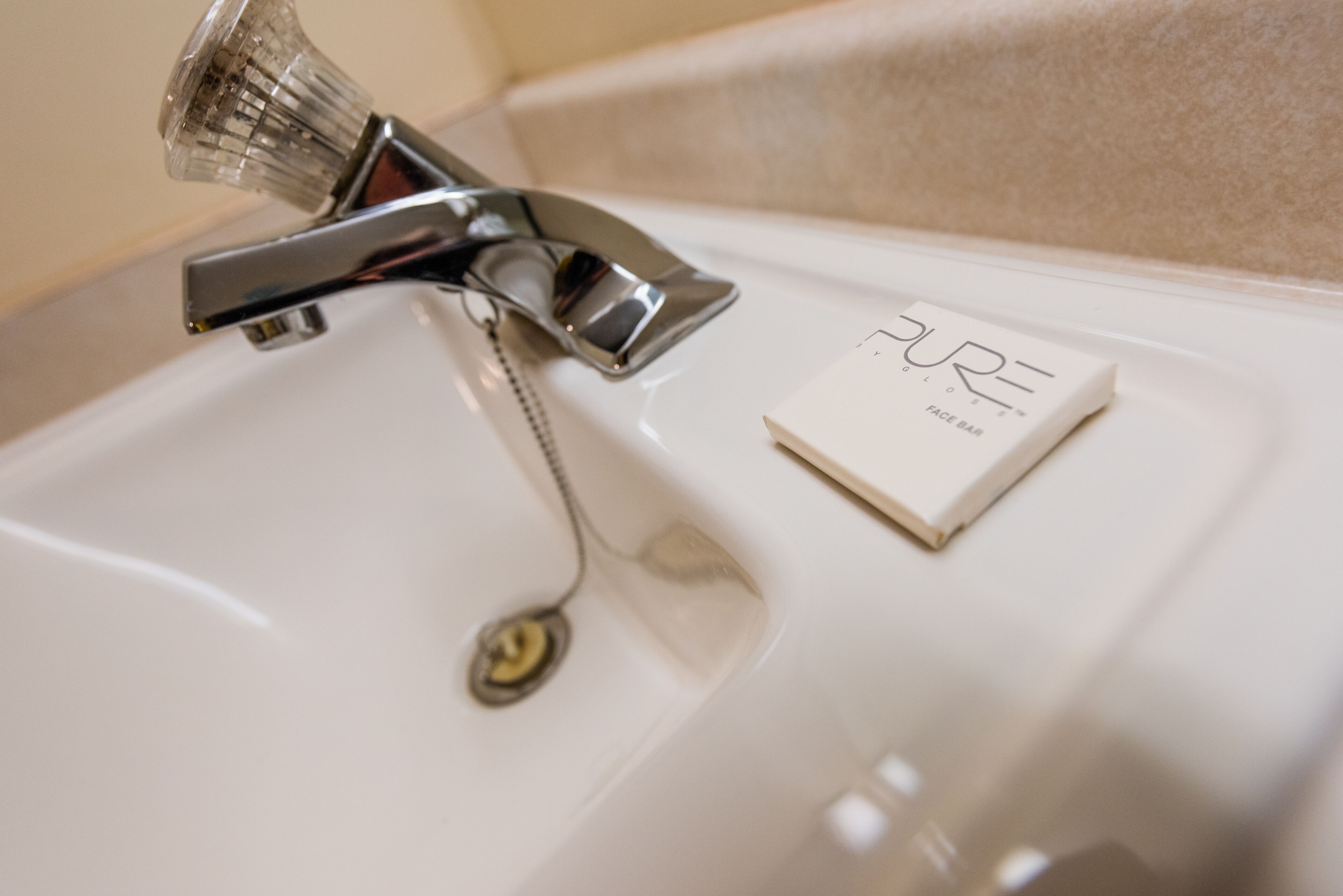 A bathroom sink with a chrome faucet and a soap bar labeled "PURE".