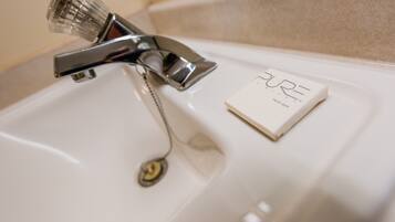 A bathroom sink with a chrome faucet and a soap bar labeled "PURE".