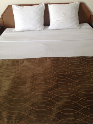A neatly made bed with a brown patterned bedspread and two white pillows. - The Ranchland Inn (Kamloops)
