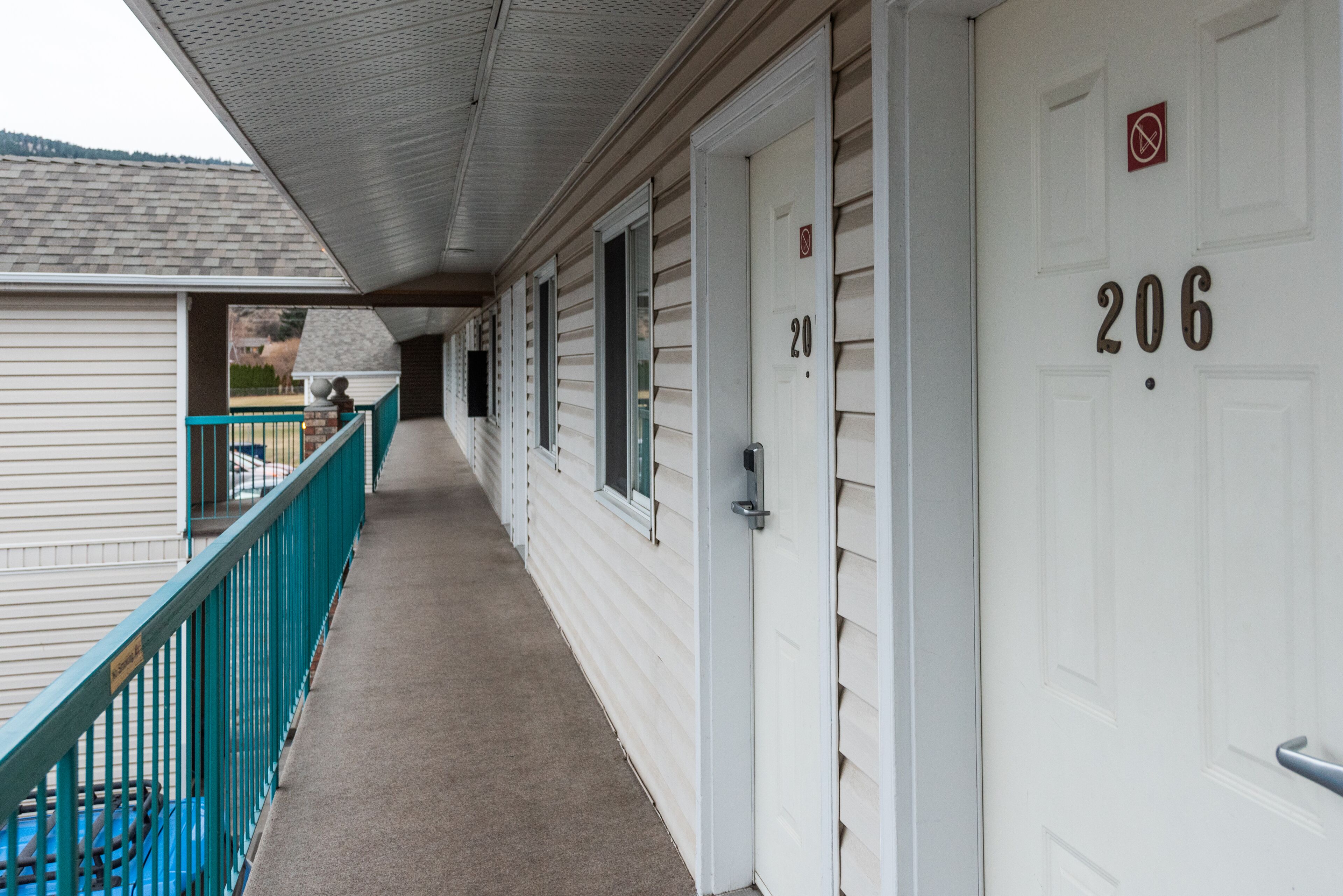 A corridor with doors numbered 206 and 21, a blue railing, and a covered walkway.