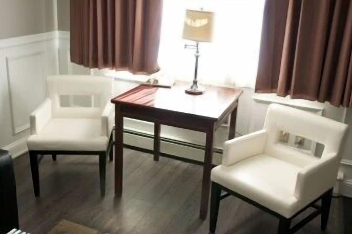 A room with two white chairs, a wooden table, and a lamp.