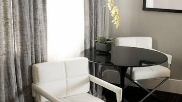 Um quarto moderno com sofá branco, mesa redonda preta e um vaso com planta.