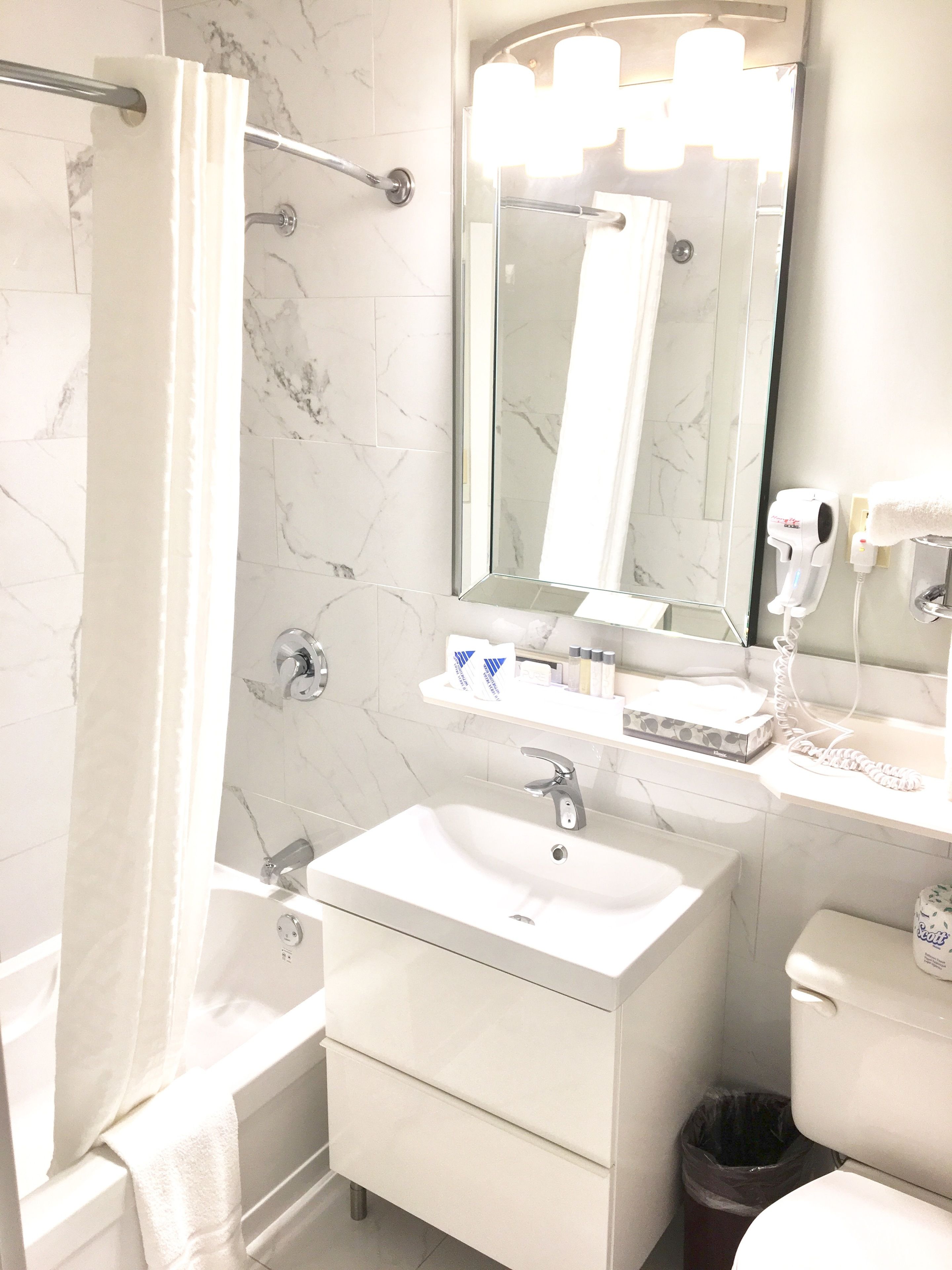Un baño con lavamanos blanco, espejo y cortina de ducha.
