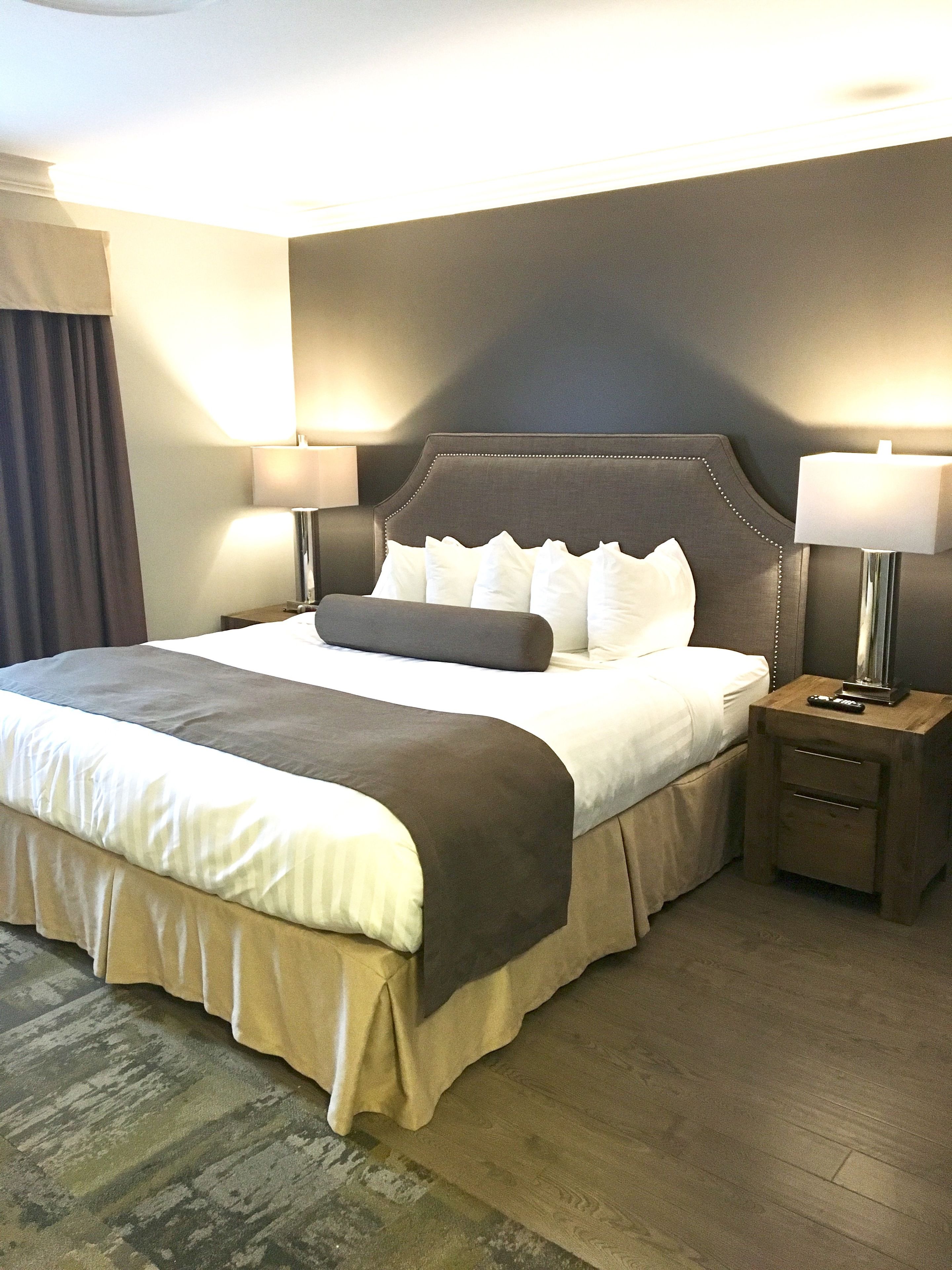 A hotel room with a large bed, two bedside tables, and a nightstand with a lamp.