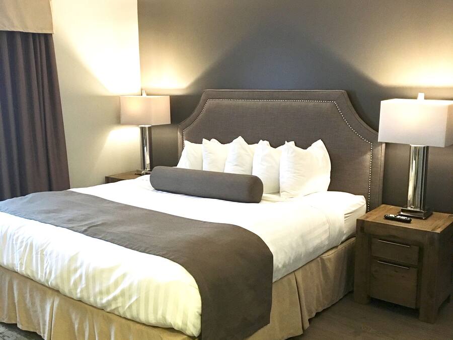 A hotel room with a large bed, two bedside tables, and a nightstand with a lamp.