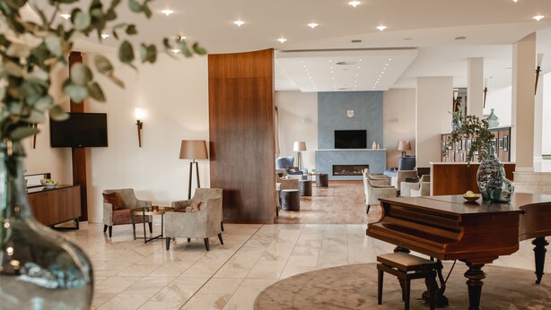 Amplia sala de estar con piano, asientos cómodos, televisor y chimenea.