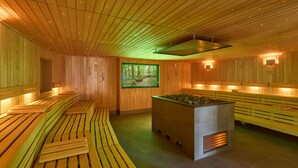 Una sauna con bancos de madera y un elemento central de piedras calientes.