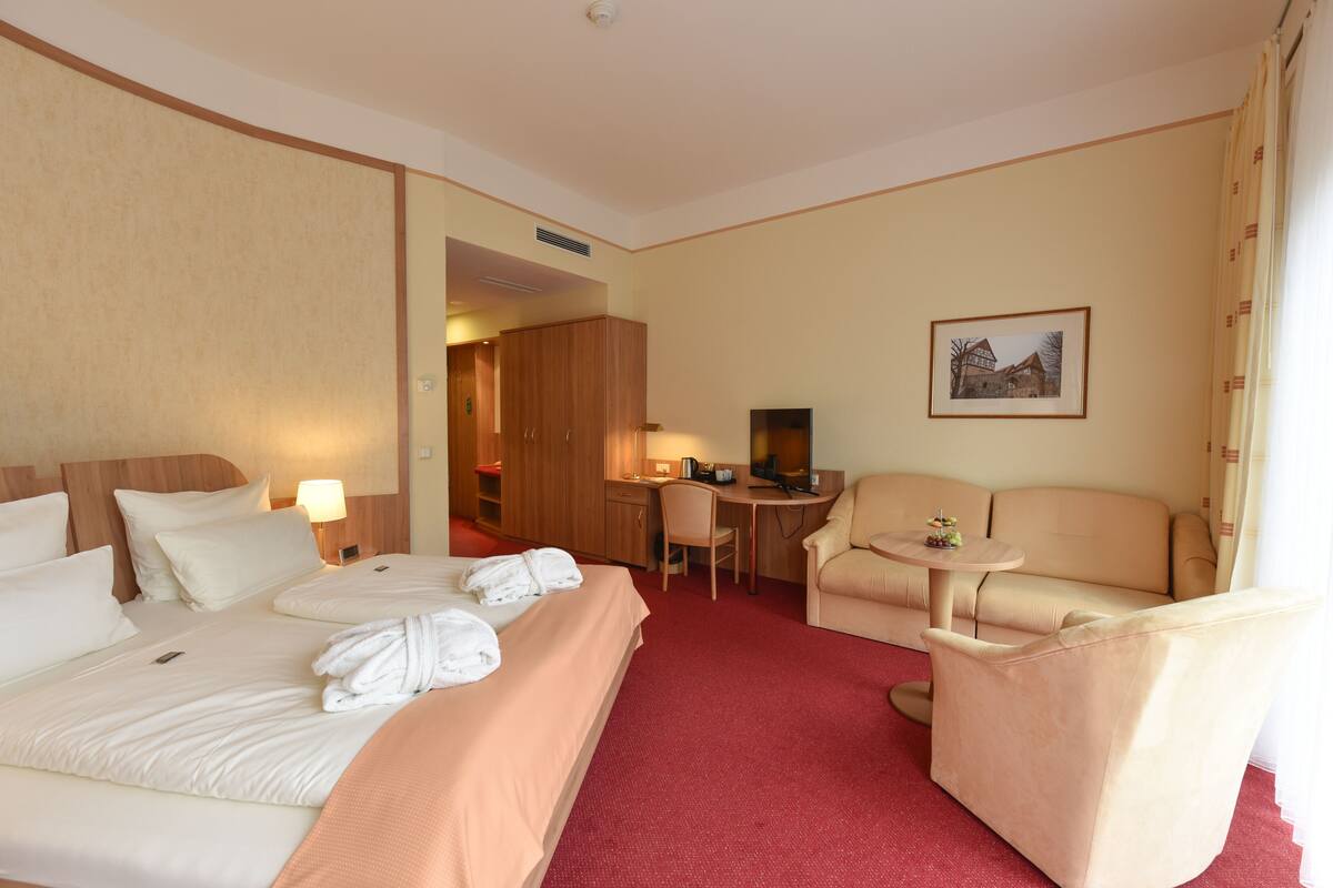 Una habitación de hotel con una cama grande, un escritorio, una silla y un sofá.